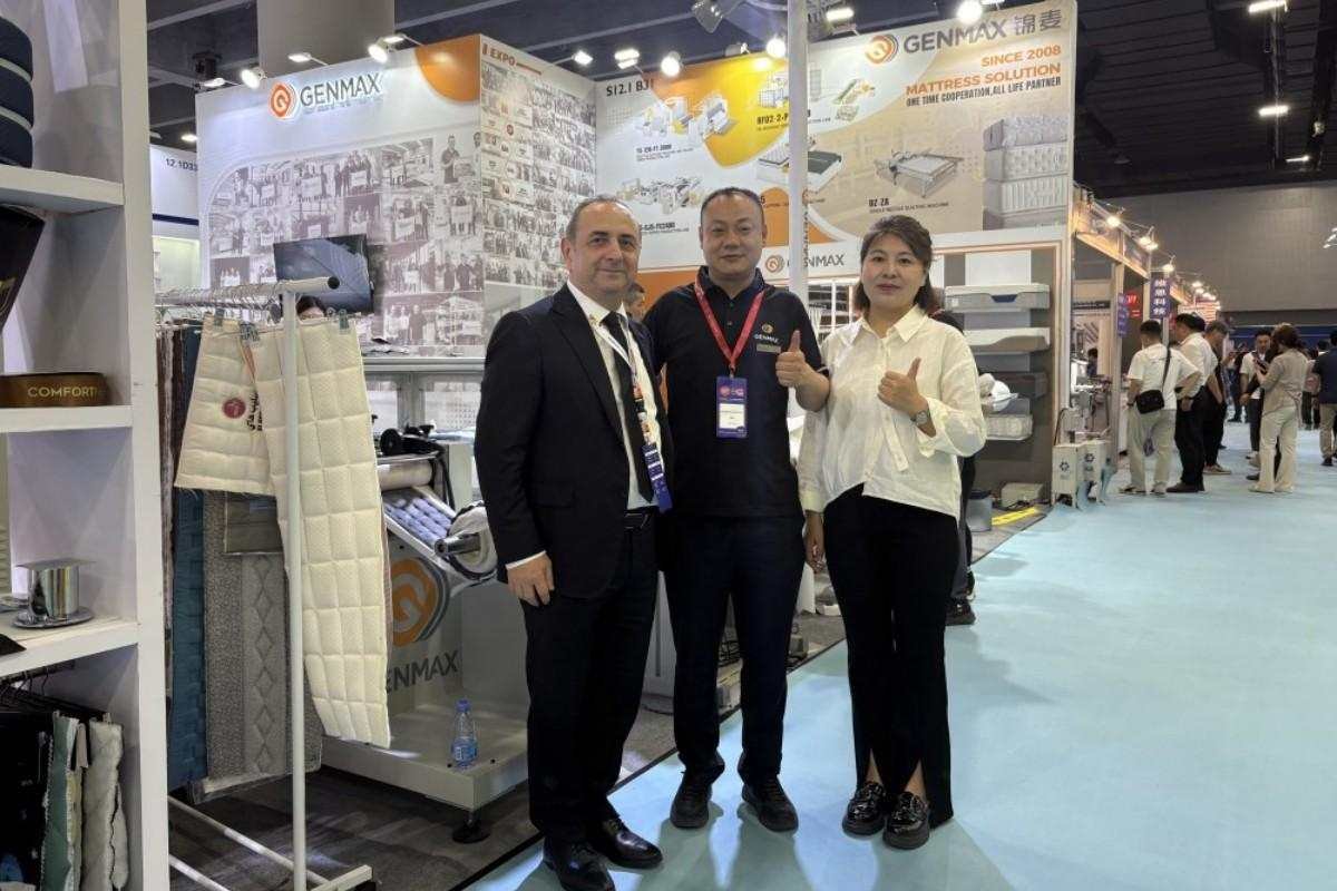 GENMAX team and customer posing for a photo in front of the showcased quilting machine at CIFF Guangzhou.
