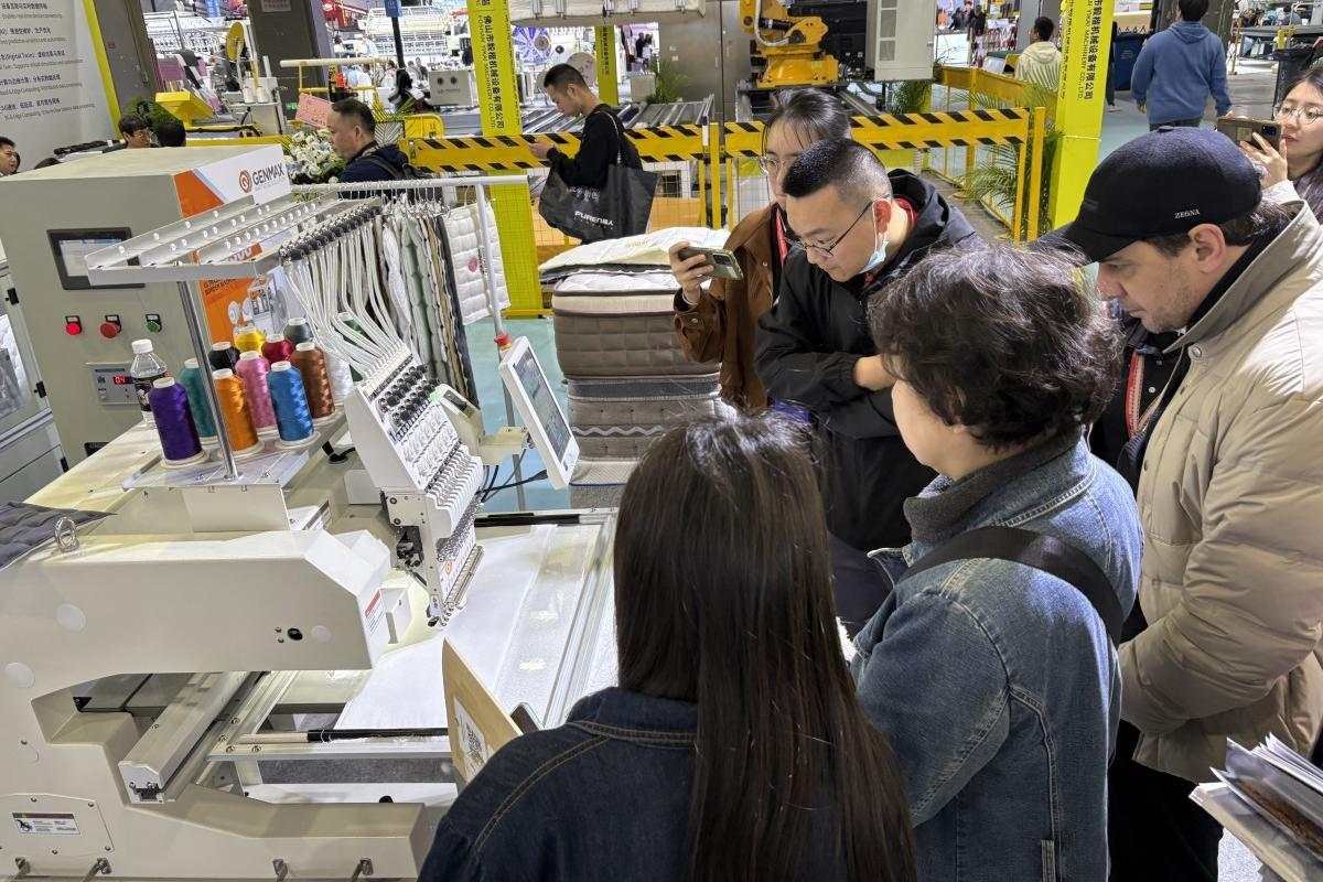 Customer reviewing various finished product samples produced by GENMAX machinery at the CIFF booth.