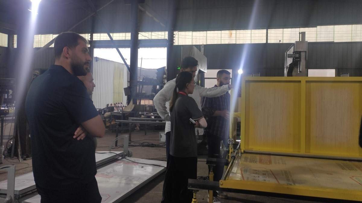 Iraqi guests attentively watching a sponge cutting machine demonstration at our manufacturing facility with technical specialists explaining the operational features.