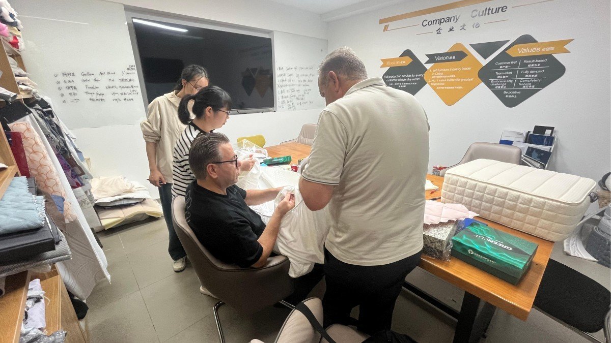 Mattress industry professionals from Jordan carefully inspecting foam and spring mattress samples in the company showroom during their factory visit.