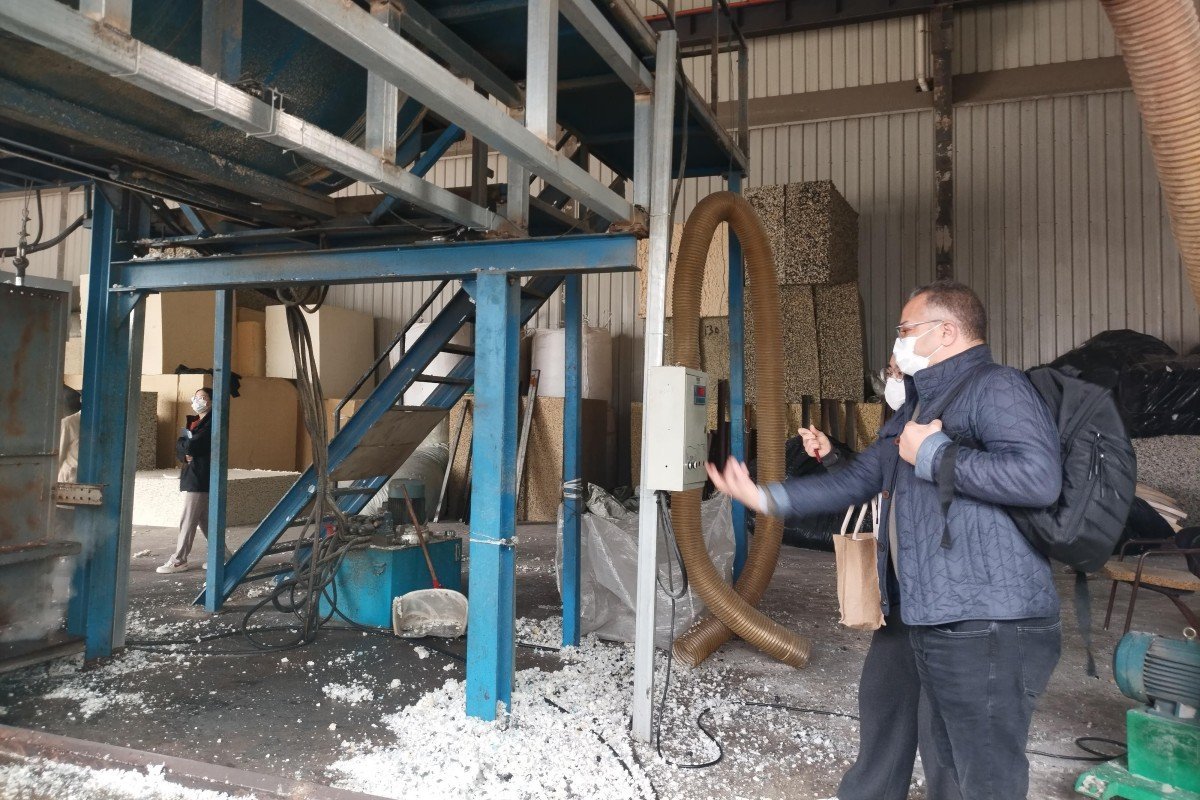 Business delegates from Morocco's foam plastics industry examining the technical components of an advanced foam recycling machine during their factory visit.