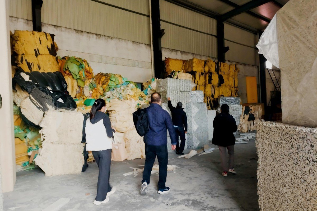 Textile industry representatives from Morocco examining compressed waste baled foam materials at the preprocessing stage of the foam recycling operation.