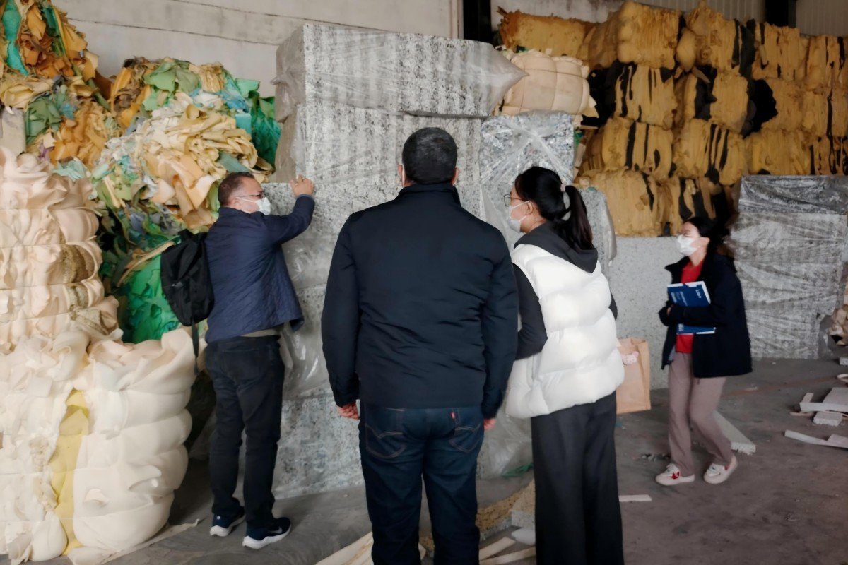 Moroccan entrepreneurs assessing the quality of compressed waste foam bales prepared for the recycling process in the factory's material preparation area.