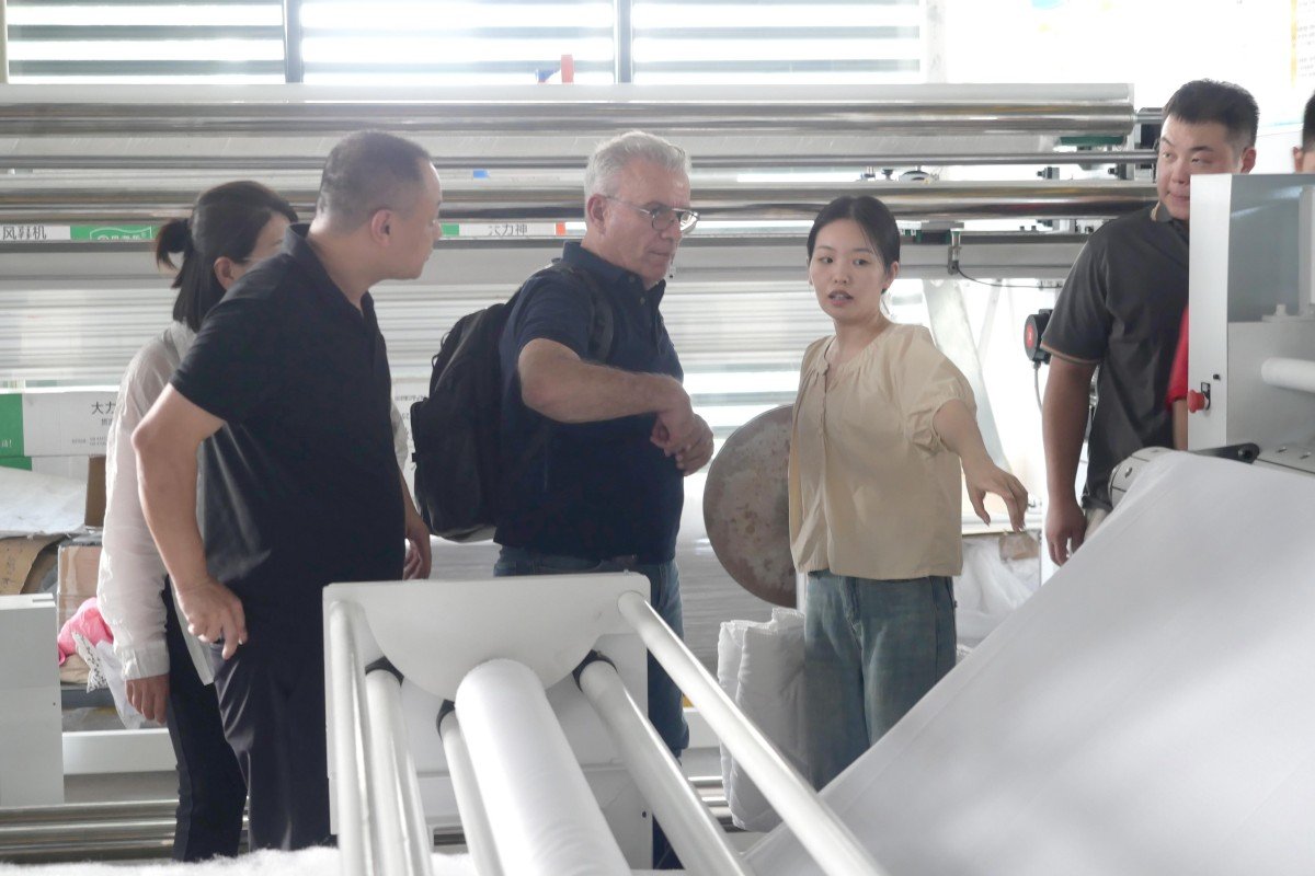Mexican delegation from Puebla watching an industrial quilting machine in operation during their technical demonstration at the manufacturing plant