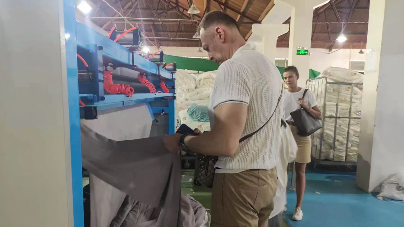 Customers examining the quality of finished fabric produced by the manufacturing machine
