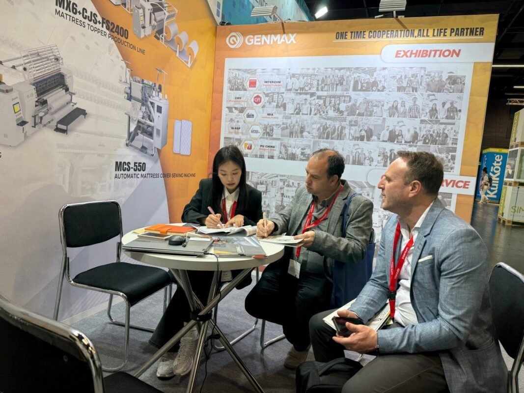 Frank, GENMAX's head engineer, engaged in a detailed technical discussion with mattress industry professionals about customized production solutions at Interzum Cologne 2025.