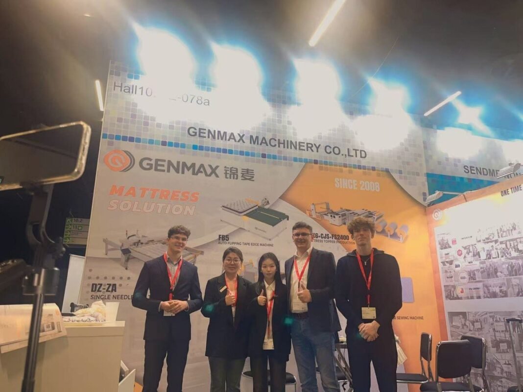 GENMAX's distinctive orange booth at Hall 10.1, E-078a during Interzum Cologne 2025, where the company will showcase their latest mattress machinery innovations.