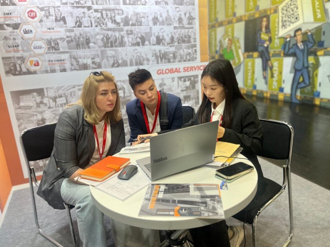Technical specialists from GENMAX providing detailed consultation to international mattress manufacturers at their Interzum 2025 exhibition booth in Cologne.