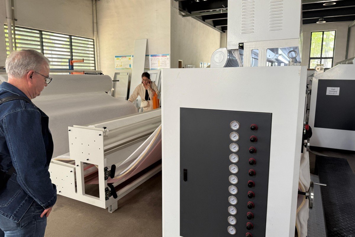 Mexican textile manufacturer carefully inspecting the mechanical components and ultrasonic bonding system of the needle-free quilting machine during a detailed technical assessment.