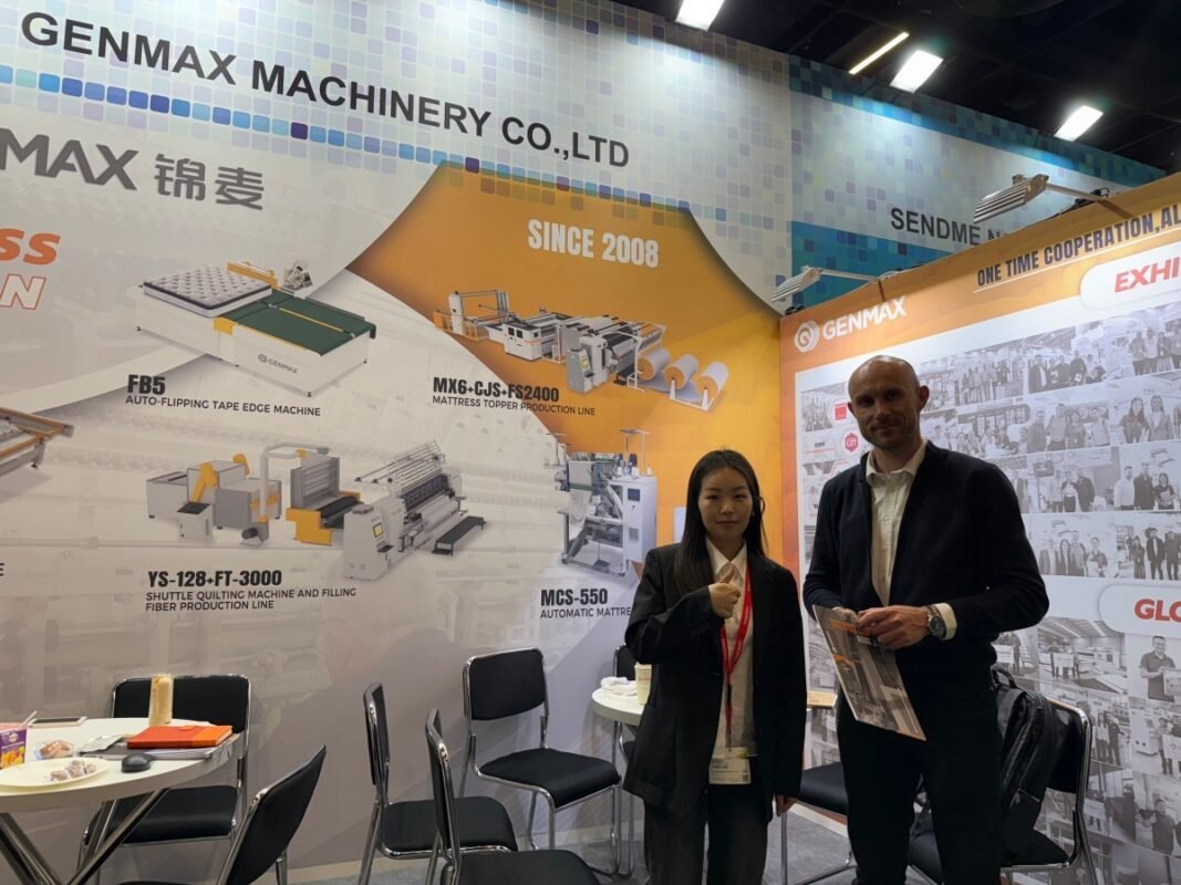 Manufacturing specialists from Poland engaging with GENMAX representatives about advanced quilting machinery during Interzum Cologne 2025 furniture production exhibition.