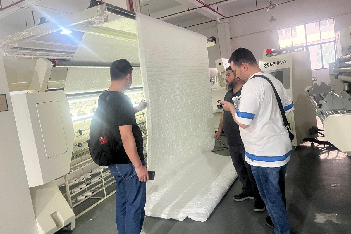 Saudi Arabian business delegates evaluating the quality of quilted mattress panels produced by the demonstration machine during their comprehensive factory inspection visit.