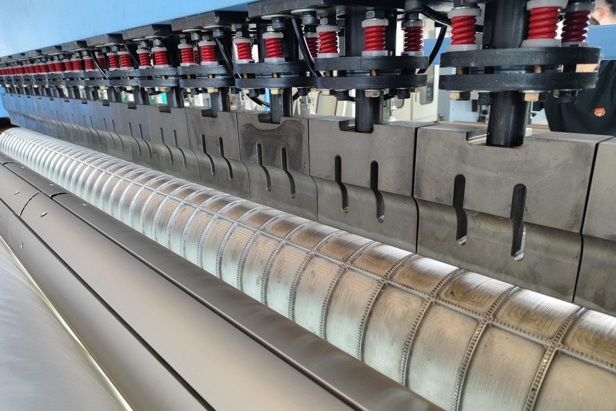 Close-up detail of the precision-engineered flower pattern embossing roller used in ultrasonic quilting machines to create decorative designs on textile products without traditional stitching.